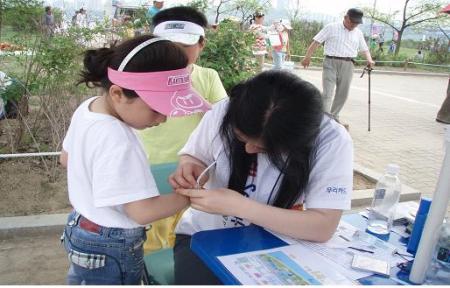캠페인 자원봉사자들이 어린이에게 미아방지 네이텍을 달아주고 있다. ⓒ2007 welfarenews