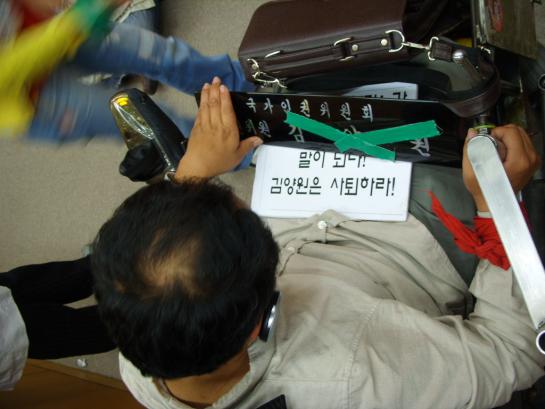 인권단체 활동가와 한 장애인이 김양원 위원의 이름패 위에 녹색 테이프를 붙이는 퍼포먼스를 진행하고 있다. ⓒ2008 welfarenews