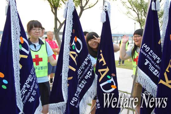 자원봉사에 참여한 학생들이 한국장애인관광레저진흥회 깃발을 들고 있다. 한 학생이 사진기를 향해 장난 가득한 포즈를 취하고 있다. ⓒ2010 welfarenews