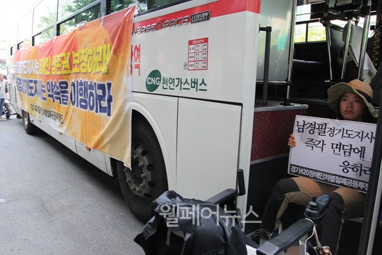 ▲ 전국장애인차별철폐연대 문애린 활동가가 7770번 버스에 올라가 손팻말 시위를 하고 있다.