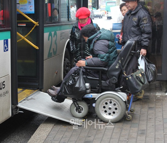 휠체어를 탄 한 장애인이 저상버스에 타고 있다.