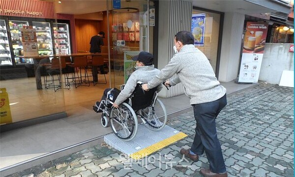 휠체어를 이용하는 주민이 경사로를 통해 가게 입구로 들어가고 있다. ⓒ성동구