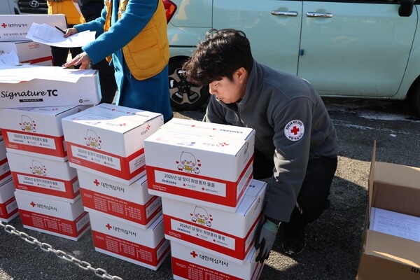 '대한적십지사 로고' 와 '2026년 설맞이 희망풍차 물품'이라고 써있는 박스를 들고 있는 남성의 모습니다. 